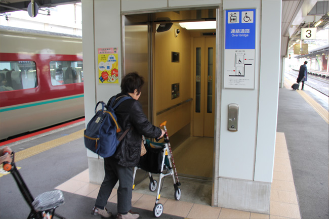 写真：シルバーカーを押しながら、駅ホームのエレベーターに