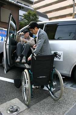 写真：タクシーから車いすに乗り込むお客様
