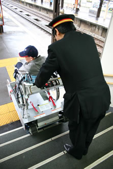写真：駅員さんがエレベーターを操作し、車いすを乗降させます。