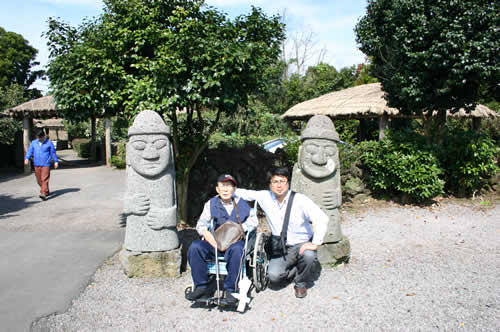 写真：済州島の像、トルハルバンの前でエスコートヘルパーと記念撮影